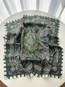 Detail shot of green paisley silk scarf with vintage patterns on a white table