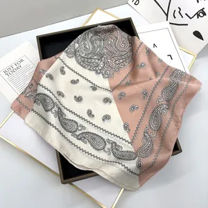 Detail showing the smooth silk texture and paisley patterns on a pink square scarf