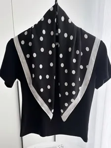 Detailed view of polka dot silk scarf draped over a black shirt with elegant satin finish