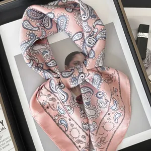 Foulard en soie rose avec motifs cachemire bleus posé sur un magazine de mode chic