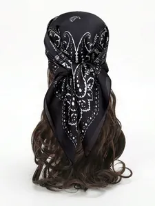 Vue détaillée d'un bandana noir en soie à motif paisley noué sur de longs cheveux ondulés