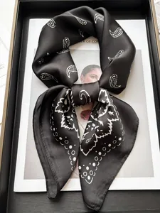Détail d'un foulard carré en satin avec imprimé cachemire blanc classique sur fond noir
