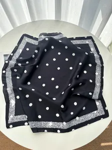 Close-up of elegant silk-like square scarf with white polka dots on black fabric
