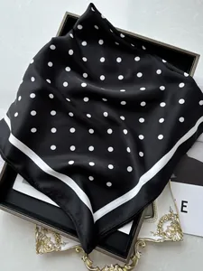 Dettaglio dell'elegante foulard in seta a pois neri e bianchi con finitura lucida