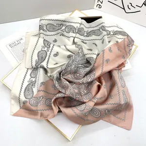 Detail of bicolored paisley silk scarf in beige and dusty pink on a gold tray