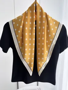 Close-up of a yellow polka dot silk scarf with contrast borders on a black t-shirt
