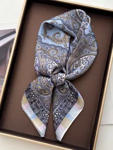 Close-up of silk square scarf with paisley pattern in blue and brown on a gold-rimmed tray