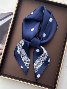 Detailed view of dark blue satin scarf with white polka dots folded in a gift box