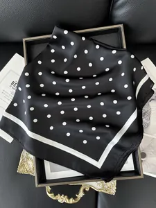 Dettaglio di un foulard in seta a pois bianchi e neri con elegante finitura satinata lucida