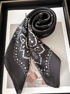 Détail d'un foulard carré en soie noire avec motif cachemire et finition satinée chic