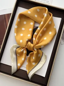 Detail of a ginger yellow satin scarf with white polka dots and elegant silk texture