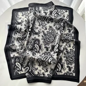 Detail shot of the black and white paisley silk scarf draped on a white round table