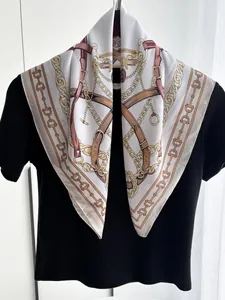 Detailed macro view of high-quality silk scarf featuring gold chain and equestrian prints