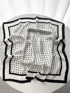 Detail of elegant black and white polka dot silk scarf with wide black hem and soft texture