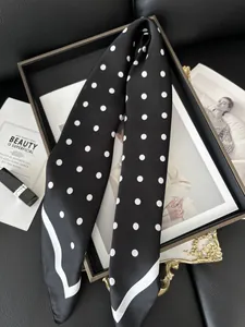 Dettaglio del foulard in seta da 70 cm a pois su un vassoio vintage dorato elegante