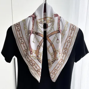 Detail of silk-feel scarf draped over a black shirt showing gold chain and buckle patterns