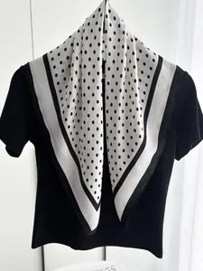 Detailed view of polka dot silk scarf draped over a black top with elegant drape