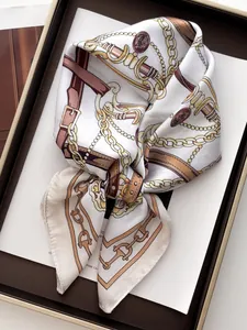Detail of silk-like square scarf with gold chain and leather belt patterns on cream base