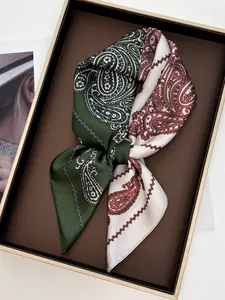 Detail of two-tone paisley silk scarf in forest green and beige on a display plate