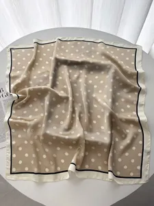 Detailed close-up of beige silk scarf with white polka dots and elegant contrast edges