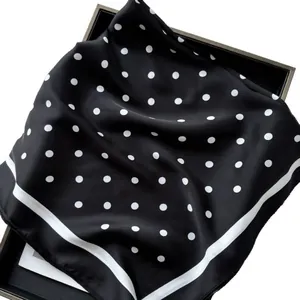 Foulard in seta 70 cm nero a pois bianchi con bordi a righe esposto su un vassoio