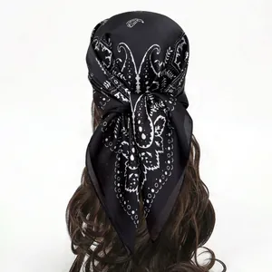 Foulard en soie noir avec motif paisley porté comme un bandeau élégant sur les cheveux