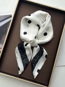 Close-up of silk scarf with black polka dots and wave patterns on a luxury tray