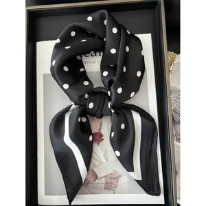 Foulard di seta nero 70cm con pois bianchi e bordo a righe su vassoio per riviste