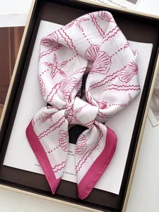 Detailed shot of silk scarf with shell print and nautical patterns in a premium gift box