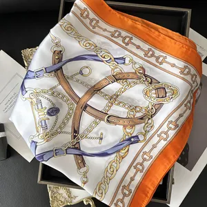 Detailed view of horse-bridle print silk scarf with chain pattern and orange borders