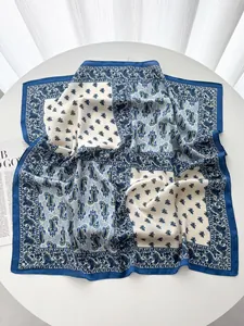 Detailed view of dark blue and beige paisley print silk scarf with satin finish texture