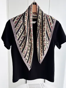 Close-up of silk scarf with red horse prints styled on a black shirt with a wooden hanger
