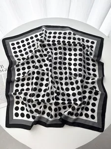 Close-up of a polka dot silk scarf with striped borders on a minimalist white table