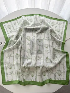 Close-up of silk scarf featuring green sea shell print and delicate rolled edges