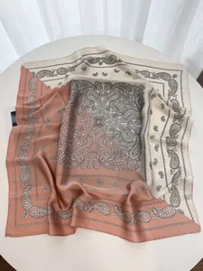 Detail of satin square scarf with paisley pattern and two-tone拼接 design on white table