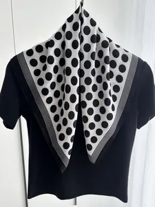Classic black and white polka dot silk scarf draped over a minimal black crewneck top
