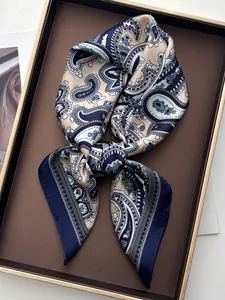 Detailed close-up of navy paisley satin silk scarf folded in a luxury display tray