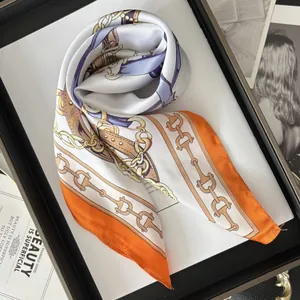 Close-up of silk-textured square scarf with gold chain and equestrian print on black tray