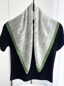 Detail of silk-like scarf with shell and starfish prints draped on a black t-shirt