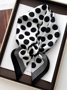 Close-up of silk scarf with classic black polka dots and striped border in a gift box