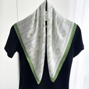 Detail of silk-like square scarf featuring green shell prints and sea star patterns