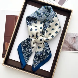 Detail of elegant ivory silk scarf with navy paisley pattern and floral motifs in a tray