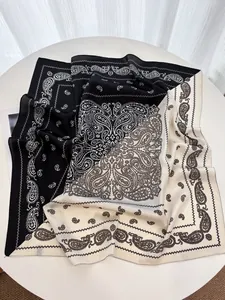 Close-up of dual-tone paisley print silk scarf with fine rolled edges on a white table