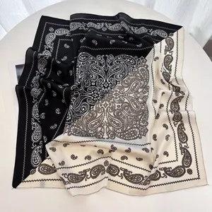 Detailed view of the paisley pattern on a black and white silk-feel square scarf