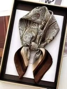 Close-up of brown and green paisley satin silk scarf with vintage pattern in a black tray