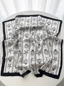 Detail view of the lightweight silk scarf featuring elegant seashell and starfish prints