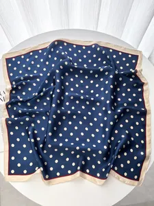 Detailed close-up of navy blue silk square scarf with polka dots on white surface