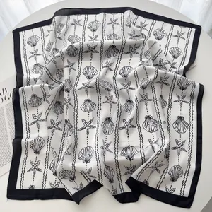 Detail of elegant silk scarf with black shell and starfish patterns on a white background