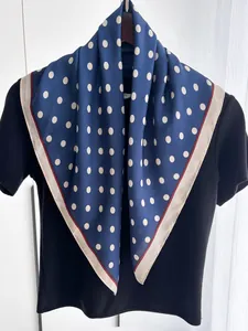 Detail view of dark blue polka dot silk scarf with elegant contrast border design