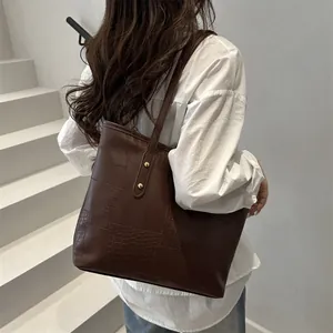 Large dark brown tote bag with mixed textures shown on model's shoulder in profile